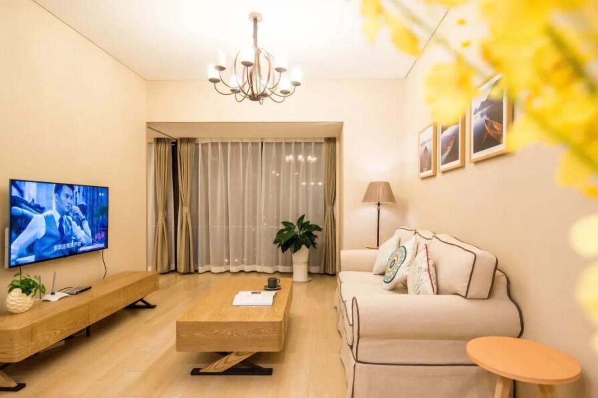 A modern living room with a television, sofa, coffee table, and a plant.