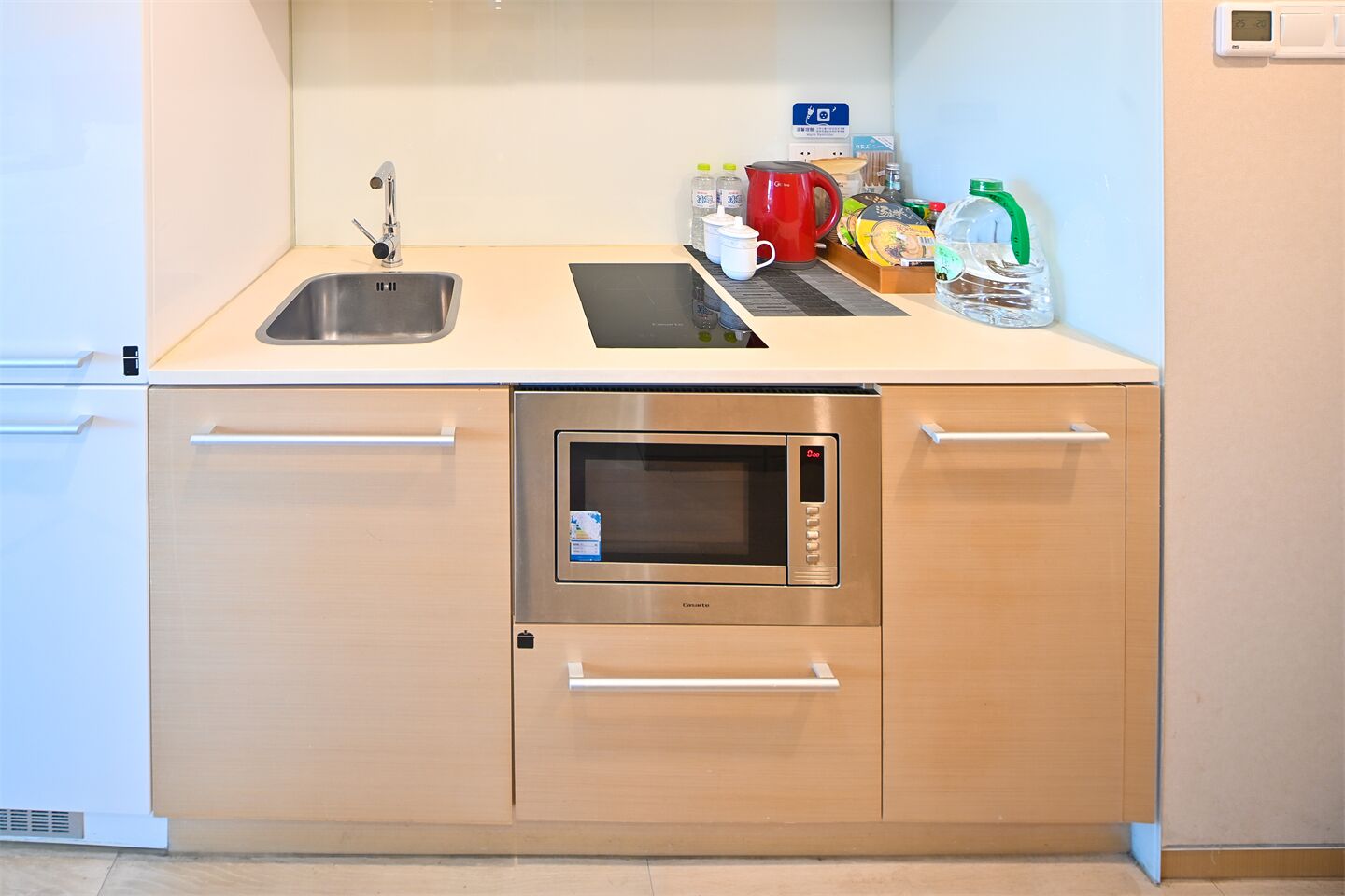 Une cuisine compacte équipée d’un évier, d’un four à micro-ondes et d’un petit plan de travail.