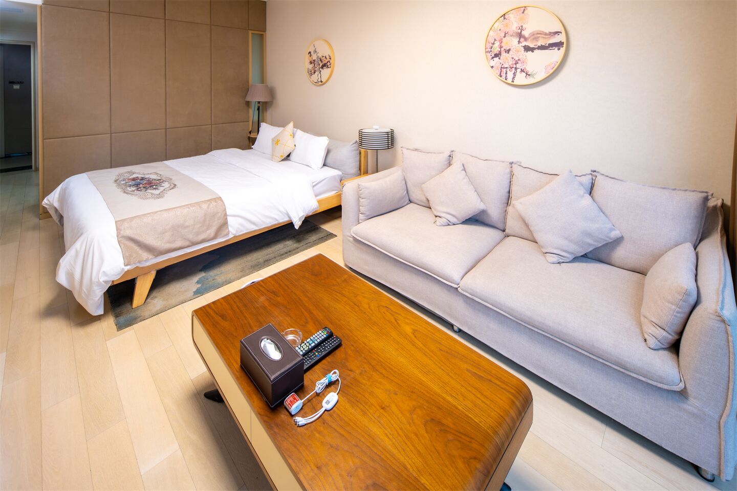 Una habitación de hotel con cama, sofá y una mesa de centro con un control remoto.