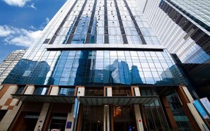 A modern high-rise building with reflective glass windows and a prominent entrance area. - qingdaowanxianghuayuan (Qingdao)