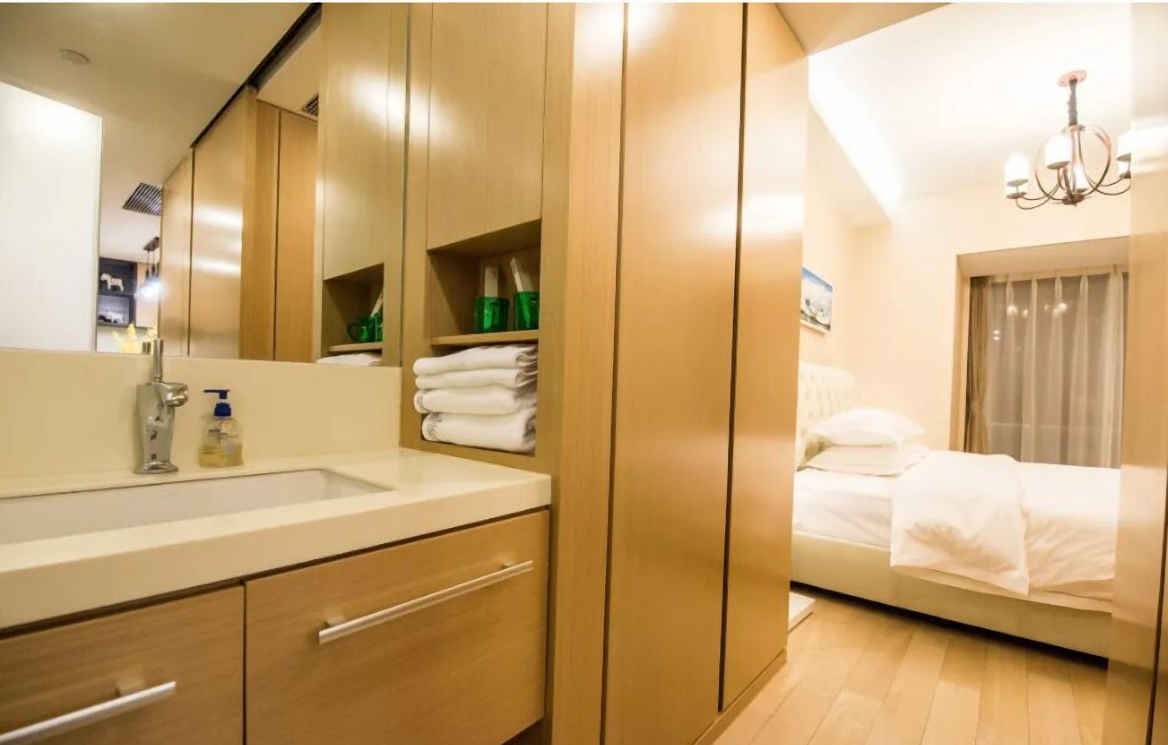 Una habitación de hotel moderna con un espejo grande, un armario de madera y una cama con ropa de cama blanca.