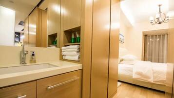 A modern hotel room with a large mirror, wooden wardrobe, and a bed with white linens.