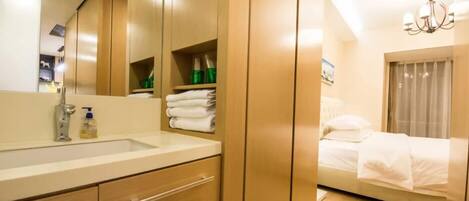 Una habitación de hotel moderna con un espejo grande, un armario de madera y una cama con ropa de cama blanca.