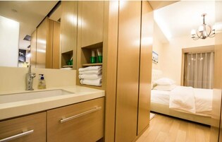 Una habitación de hotel moderna con un espejo grande, un armario de madera y una cama con ropa de cama blanca.