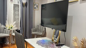 Una sala moderna con televisor de pantalla plana, una mesa de comedor y sillas tapizadas en gris.