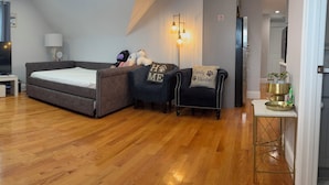 Un dormitorio con cama, una silla, una mesita, una lámpara y una lámpara de techo.