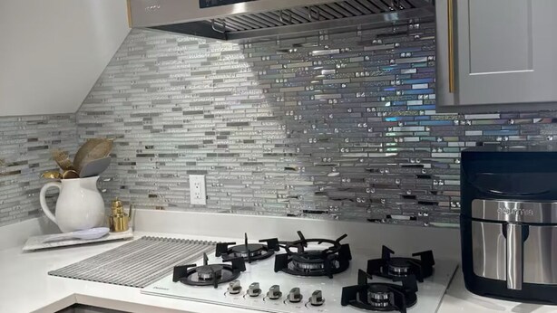 Una cocina moderna con extractor de acero inoxidable, estufa a gas y cafetera.