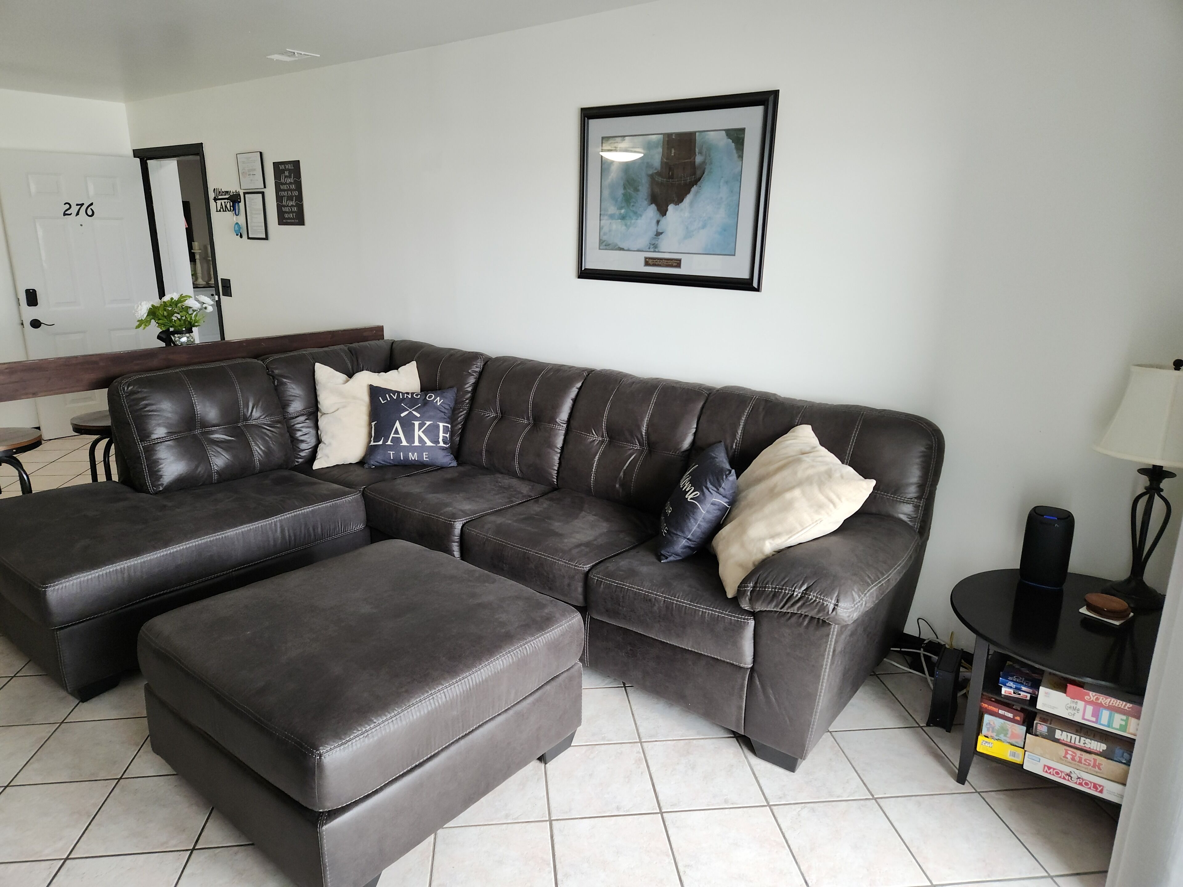 A modern living room with a sectional sofa, a small table, and a framed picture on the wall.