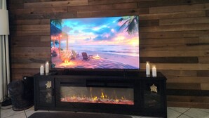 Ein Flachbildfernseher an einer Holzwand, darunter ein Kamin.