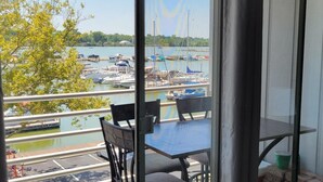 Ein Balkon mit Tisch und Stühlen mit Blick auf eine Marina und Boote.