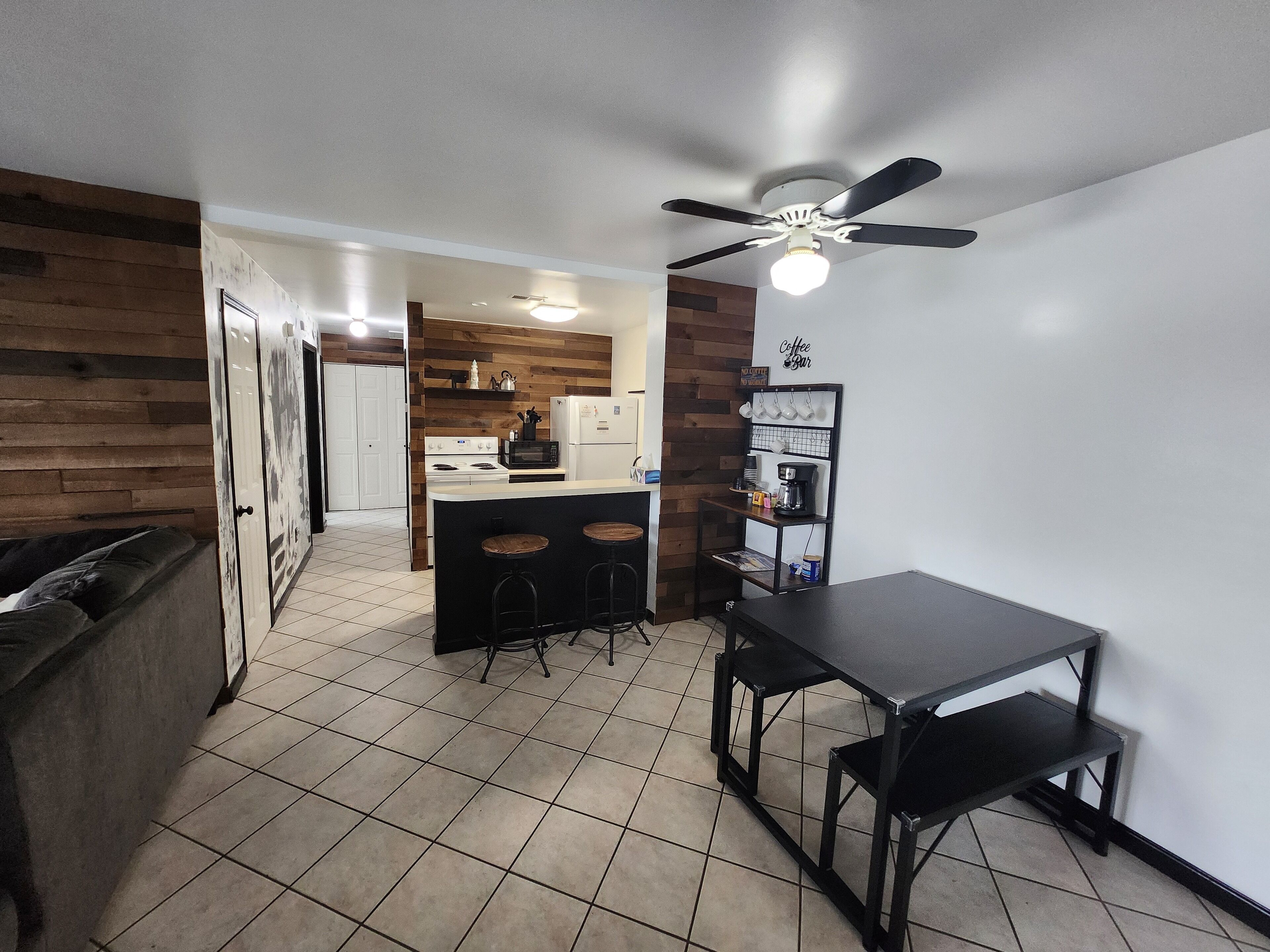 A compact kitchen with a central island, a ceiling fan, and a coffee bar.