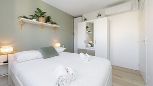 Een keurig opgemaakte slaapkamer met een bed, nachtlampjes, een kledingkast en een plank met planten.