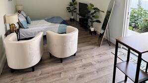 Un dormitorio moderno con una cama, dos sillones, un escritorio y un televisor.