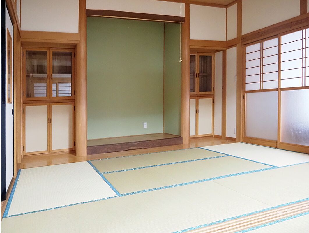 A traditional Japanese room with tatami flooring, sliding doors, and wooden frames.