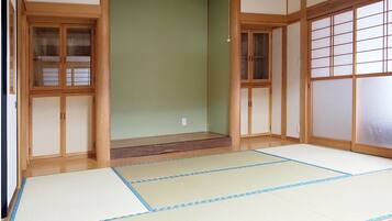 A traditional Japanese room with tatami flooring, sliding doors, and wooden frames.