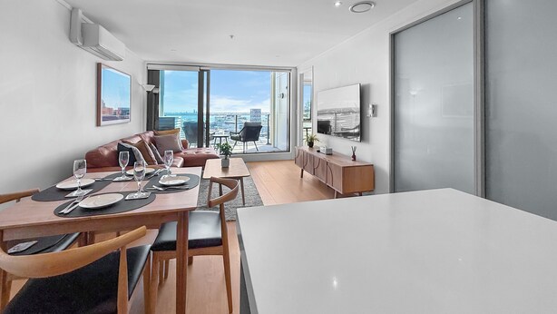 Una sala de estar moderna con comedor, ventanas amplias y vistas a la ciudad.