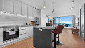 Una cocina moderna con armarios blancos, horno Bosch y una isla grande con taburetes de bar.