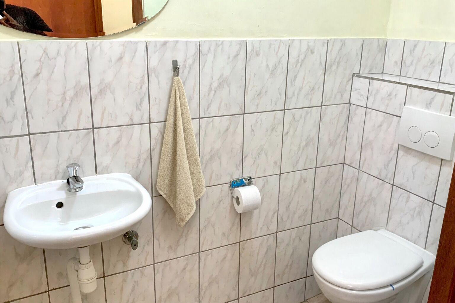 Een badkamer met een wastafel, toilet, handdoek en toiletpapier.