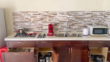 Een koelkast, een microgolfoven, een oven, kookgerei, borden en bestek