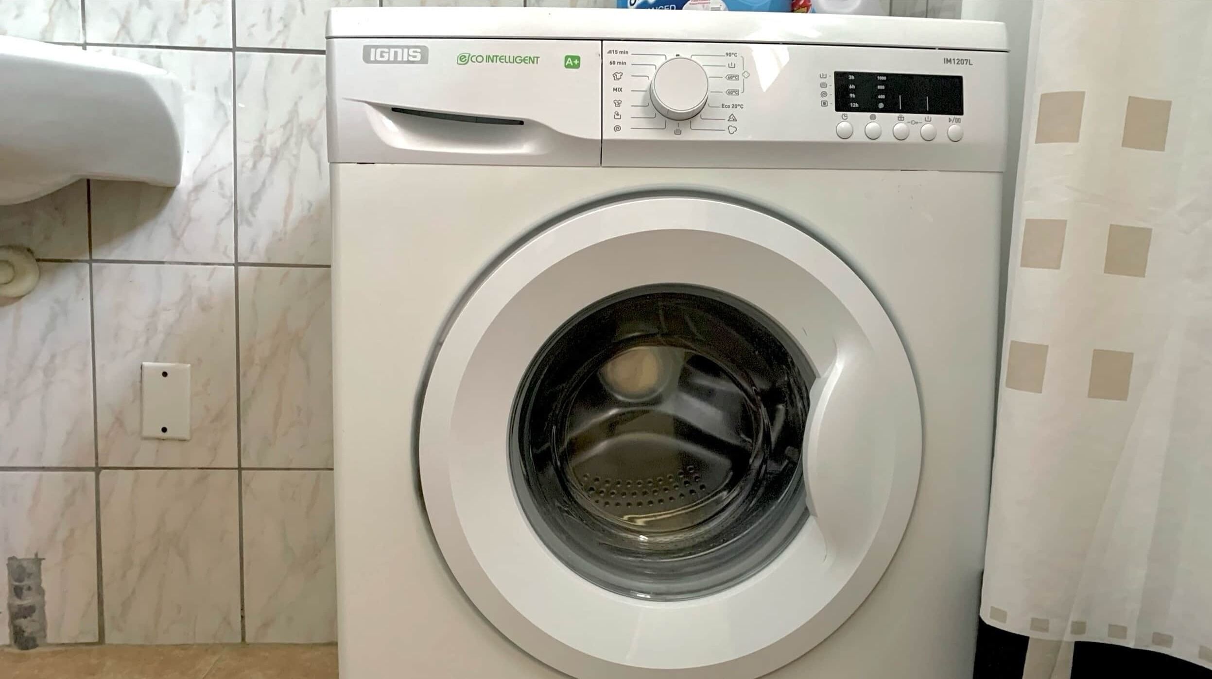 A front-loading washing machine with a digital display, control panel, and a water inlet.