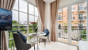 En balkon med spisebord, stole, fjernsyn og gardiner.