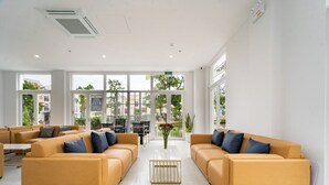 En rummelig lobby med to sofaer, der vender mod et centralt kaffebord, store vinduer med udsigt over det fri, og en receptionsdisk i baggrunden.