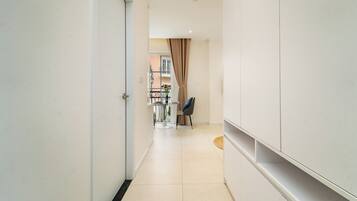A hallway with a dining area, a chair, and a table with a vase of flowers.