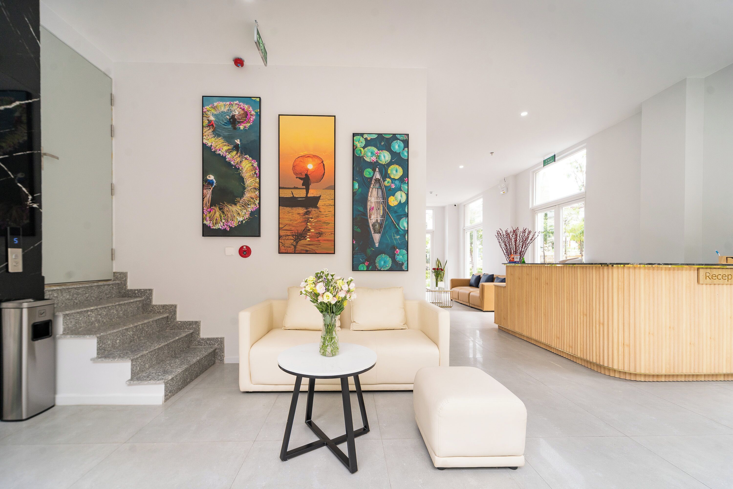 A modern hotel lobby with a reception desk, a sofa, a coffee table, and artwork on the walls.
