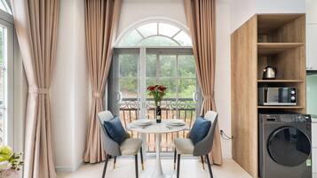 Una cocina moderna con lavadora integrada, una mesa redonda con sillas y vistas a través de un amplio ventanal.