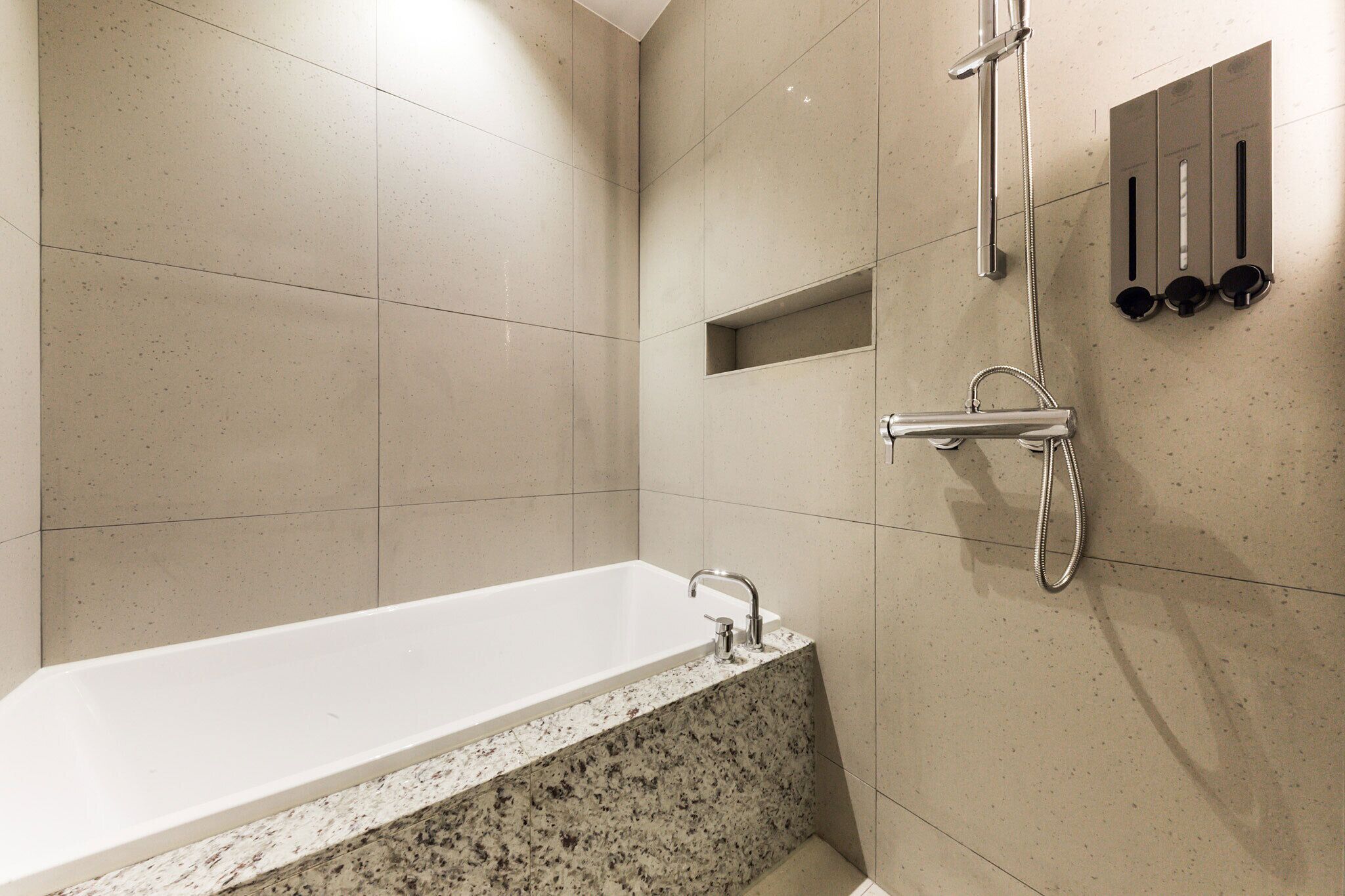 A modern bathroom with a freestanding bathtub, a showerhead, and a wall-mounted control panel.