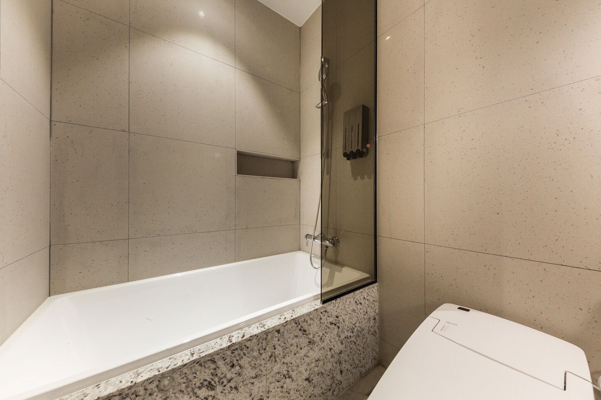 Un baño moderno con ducha envuelta en vidrio, bañera blanca y encimera de mármol.