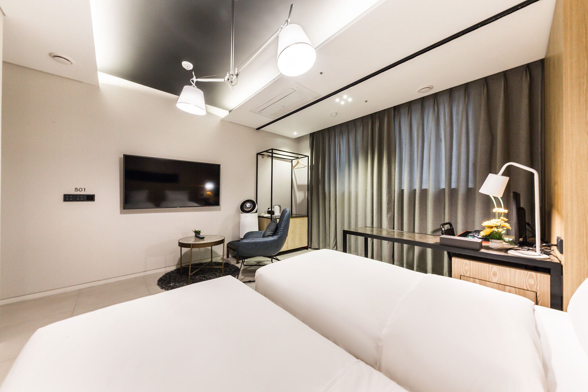 Una habitación de hotel moderna con una cama grande, un escritorio, una silla, un televisor y un espejo.