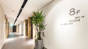 Un couloir d’hôtel avec une pancarte indiquant la chambre 801, une plante en pot et un interrupteur sur le mur.