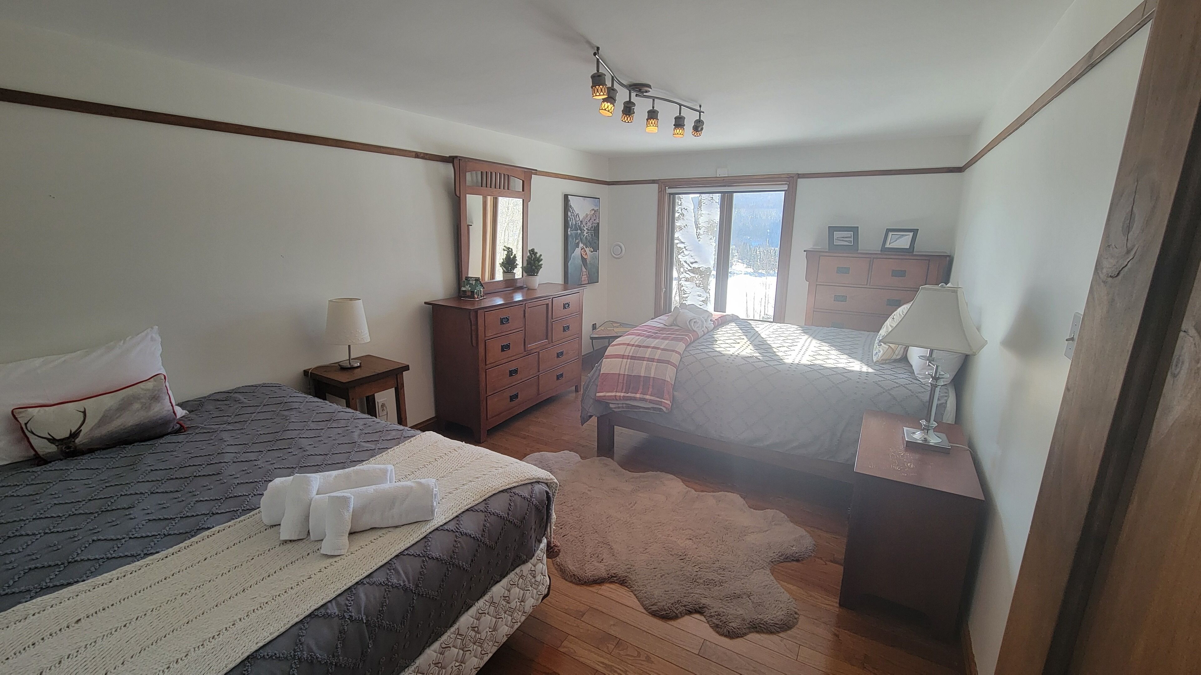 Un dormitorio con dos camas, muebles de madera, un aparador y una ventana con vistas.
