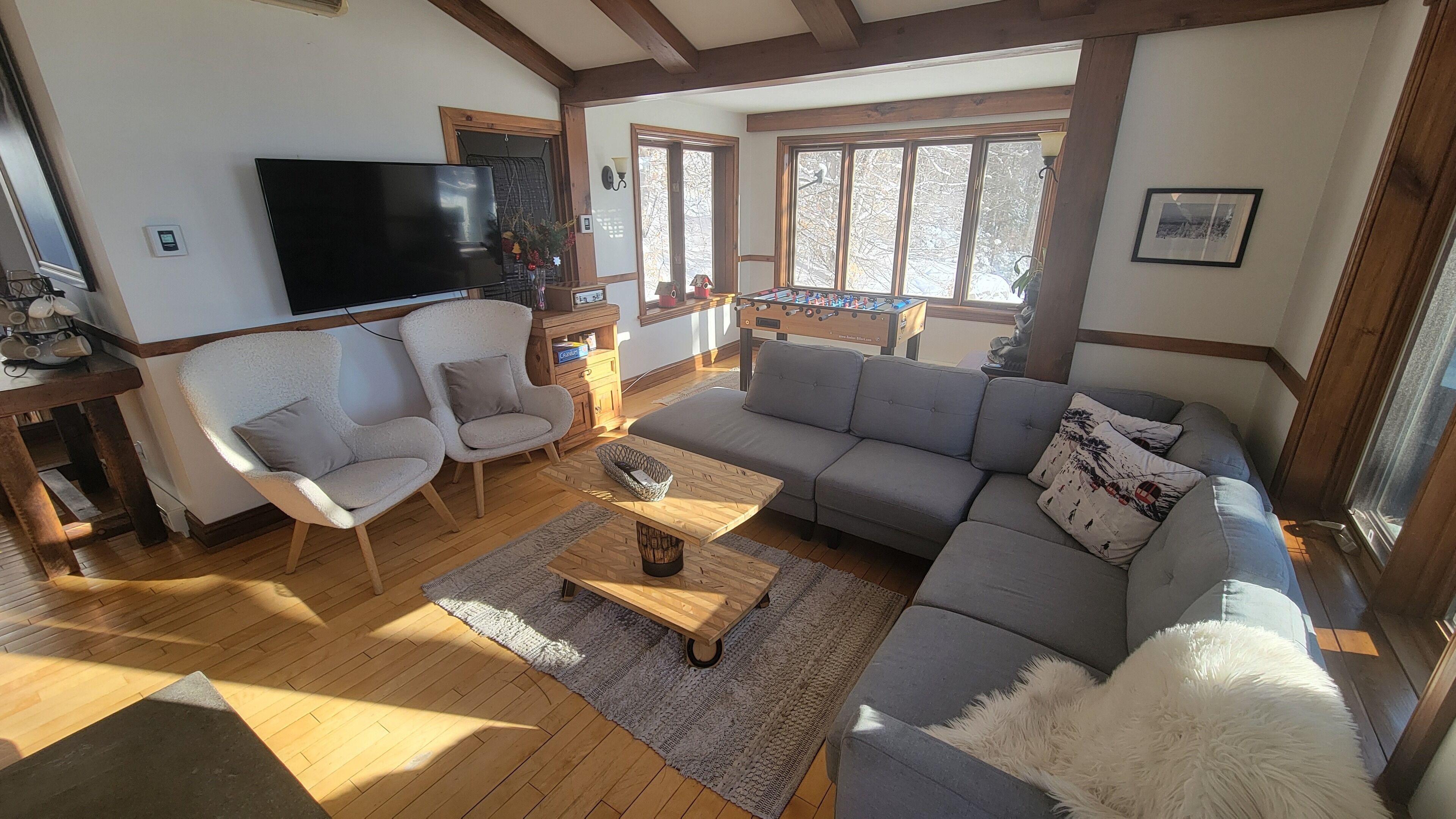 A living room with a sofa, chairs, a coffee table, a television, and a window with a view of trees.