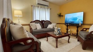 Una sala de estar con un sofá, sillones, una mesa de centro, un televisor y una lámpara.