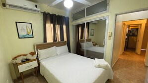Un dormitorio ordenado con cama, mesita de noche y espejo.