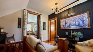 A cozy living room with a sofa, a wooden coffee table, and a large painting on the wall.