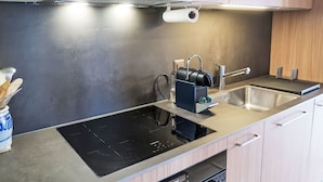 A modern kitchen with a built-in stovetop, a sink, and wooden cabinets. - Les Bluets by Interhome (Les Mosses)