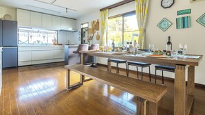 Une cuisine moderne avec un plancher en bois, une table à manger pour quatre personnes et une grande fenêtre avec des rideaux.