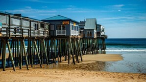 A wooden pier with multiple buildings, including a bar, extending into the ocean. - Spacious 8 Bed Suite Combo – Units 441 & 442 | Sleeps 10-12 (Old Orchard Beach)