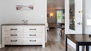 A room with a wooden dresser, a desk, and a chair. There is a door leading to another room. - Spacious 8 Bed Suite Combo – Units 441 & 442 | Sleeps 10-12 (Old Orchard Beach)