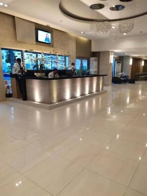 A hotel reception area with a modern design, a reception desk, and a television screen above it. - Cozy 1BR at Sea Residences Near MOA - Wifi & Netflix (Pasay)