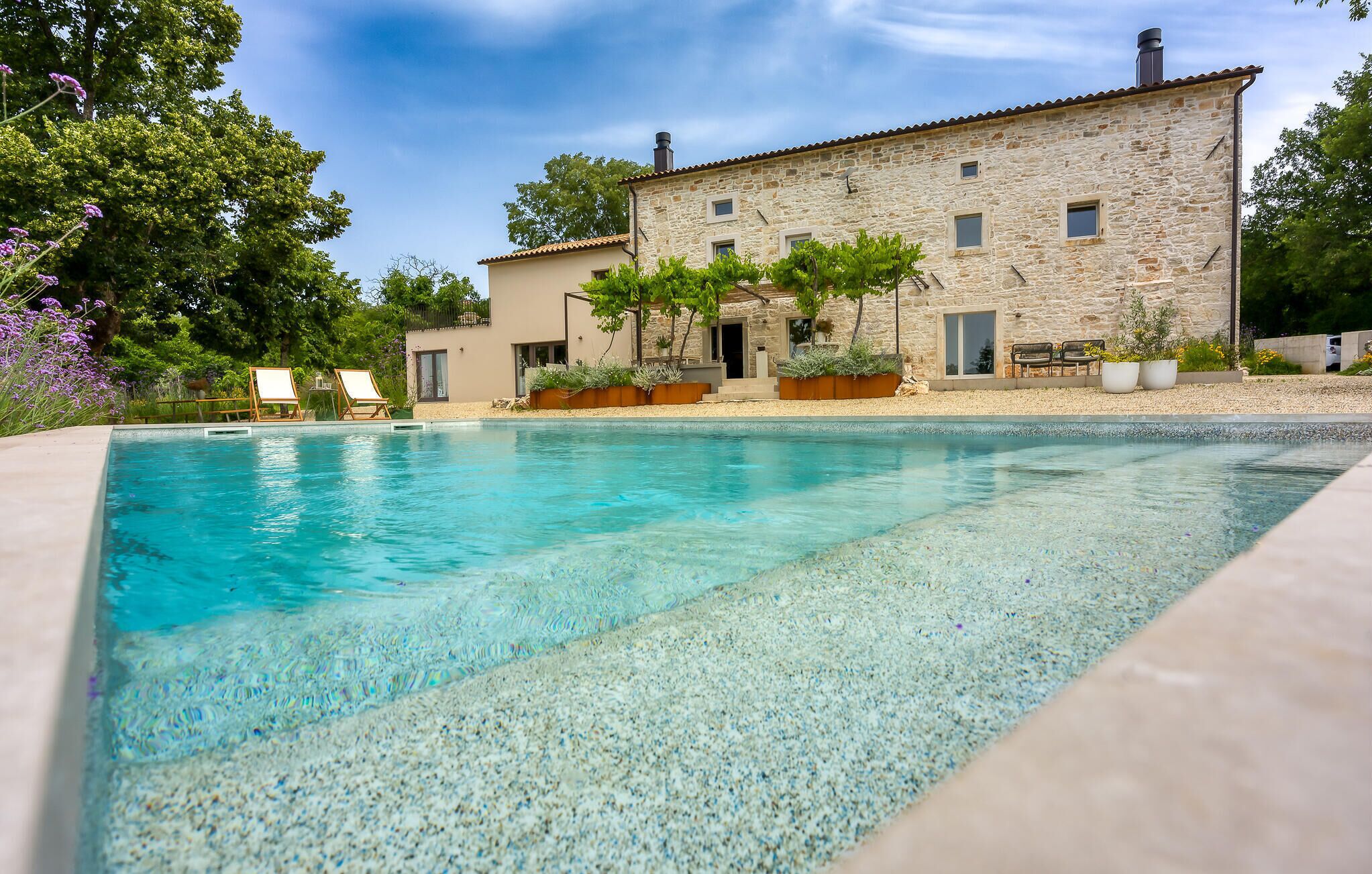 Un bâtiment en pierre avec une piscine devant.