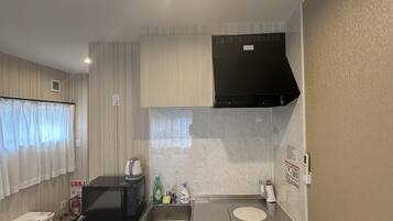 A compact kitchen with a microwave, sink, and a black range hood.
