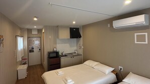 Hotellihuone, jossa on kaksi sänkyä, pieni keittiö ja kylpyhuone.