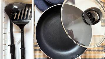 A kitchen with a frying pan, a spatula, and a lid on a mat.