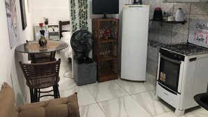 Una cuina compacta amb zona de menjador, un refrigerador, una placa de cocció i una televisió.