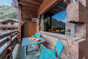 Una terraza de madera con mesa y sillas, con vista a un paisaje montañoso.