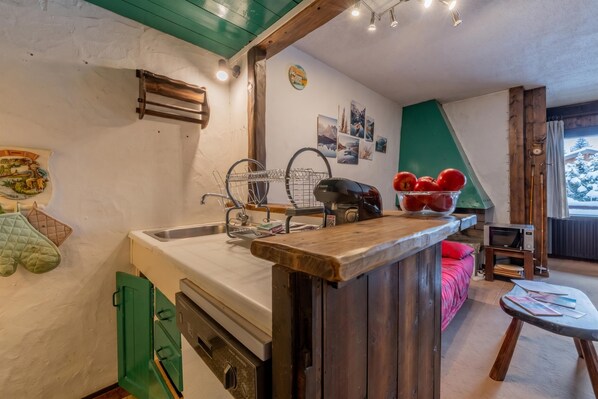 Une cuisine avec un plan de travail en bois, un évier et une fenêtre donnant sur des arbres couverts de neige.